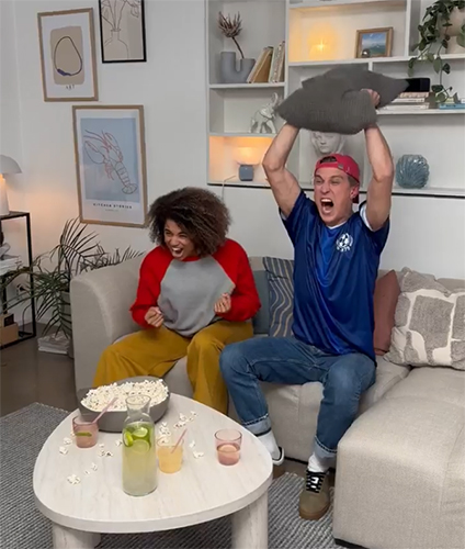 En man och en kvinna sitter i en soffa och jublar