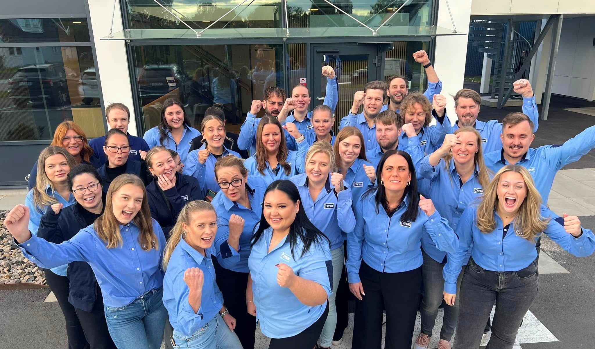 Een groepsfoto van JYSK-werknemers in blauwe shirts