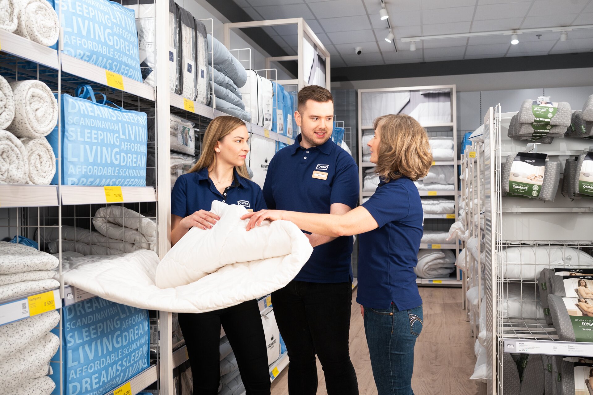 Three people standing in a store holding a duvet