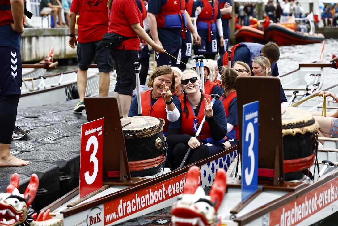 Zwei Frauen sitzen in einem Ruderboot. Sie lachen in die Kamera.