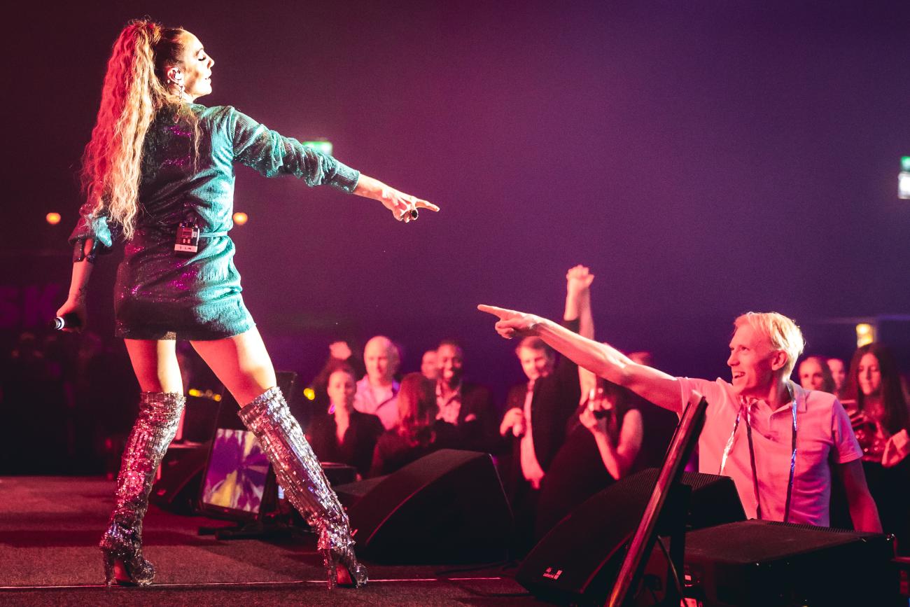 Lina Hedlund uppträder på scen. En grupp JYSK-medarbetare dansar på scenen mitt i lokalen. Foto: Joakim Thörne.