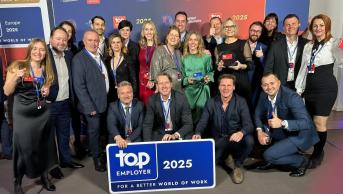 A group of people standing together with a blue Top Employer sign