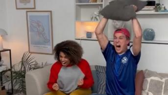 a man and woman sitting in a sofa cheering