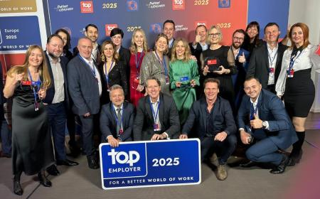 A group of people standing together with a blue Top Employer sign