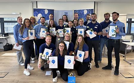 En bild på en grupp personer som håller upp sina diplom.