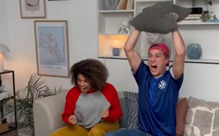 a man and woman sitting in a sofa cheering